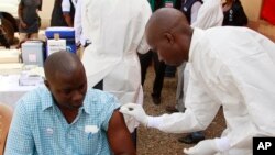 Seorang petugas kesehatan bersiap menyuntikkan vaksin Ebola kepada seorang pria di Conakry, Guinea. (Foto: Dok)