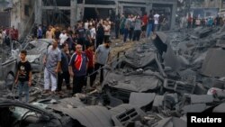 হামাসের আকস্মিক হামলার পর গাজা শহরের সমুদ্র সৈকতে শরণার্থী শিবিরে সংঘটিত ইসরাইলি হামলায় হওয়া ক্ষয়ক্ষতি পরিদর্শন করছে ফিলিস্তিনিরা। ৯ অক্টোবর, ২০২৩।