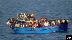 In this photo released by the Italian Navy on Monday and taken on Sunday, June 29, 2014, a boat overcrowded with migrants is pictured in the Mediterranean Sea. 