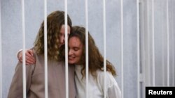 Yekaterina Andreeva and Darya Chultsova, journalists working for the Polish television channel Belsat, embrace inside a defendants' cage during a court hearing in Minsk, Belarus, Feb. 9, 2021.