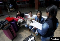 FILE - A Colombian health worker gives travelers information on how to prevent the spread of the Zika virus, at the main bus terminal in Bogota, Colombia, Jan. 31, 2016.