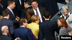 Kanselir Jerman Angela Merkel (berbaju kuning) bersama anggota Parlemen Jerman setelah memberikan suara mendukung perpanjangan 4 bulan program dana talangan untuk Yunani (27/2). 