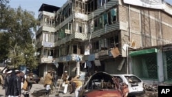 Afghan locals clears the debris near damaged vehicles outside the bank which was attacked on Saturday by Taliban insurgents in Jalalabad, east of Kabul, Afghanistan, February 20, 2011
