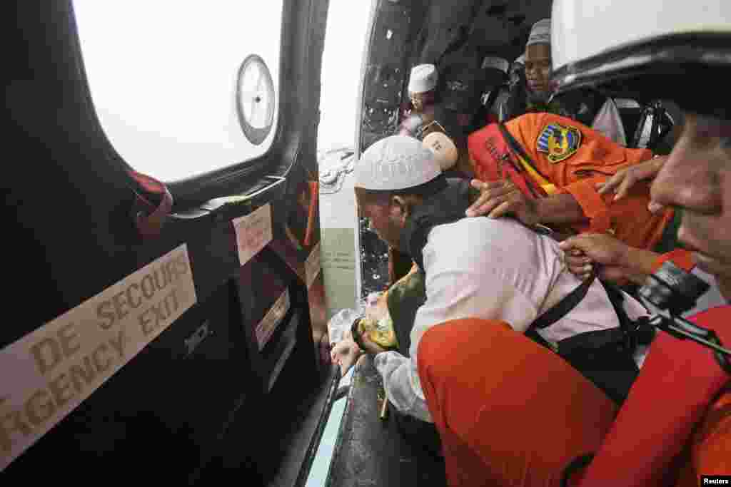 Seorang ulama menaburkan bunga setelah mendoakan para korban AirAsia bernomor penerbangan 8501 dari dalam helikopter Angkatan Udara RI yang melintasi Laut Jawa dari Pangkalan Bun, Kalimantan Tengah (6/1).