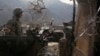 An Afghan National Army (ANA) soldier is seen through damaged glass as he keeps watch at the Forward Base in Nari district near the army outpost in Kunar province, Feb. 24, 2014. 