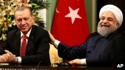 FILE - Iran's President Hassan Rouhani, right, laughs during a during a joint press conference with Turkey's President Recep Tayyip Erdogan following their meeting at the Saadabad Palace in Tehran, Iran, Oct. 4, 2017.