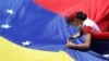 Una seguidora del líder de la oposición venezolana Juan Guaidó, a quien muchas naciones reconocen como el gobernante interino legítimo del país, fija una bandera durante una manifestación contra el gobierno del presidente Nicolás Maduro. [Archivo]