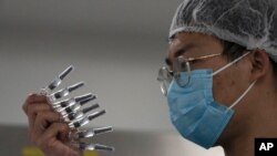 Seorang karyawan memeriksa jarum suntik Vaksin SARS CoV-2 untuk Covid-19 yang diproduksi oleh SinoVac di pabriknya di Beijing, 24 September 2020. (Foto: AP)