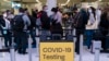 Pelancong mengantre untuk pemeriksaan di dekat tanda tempat pengujian COVID-19 di Bandara Internasional Los Angeles di Los Angeles pada 24 November 2021. (Foto: AP)