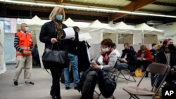 Orang-orang antre setelah menerim suntikan vaksin di COVID-19 di lokasi vaksinasi di Fontainebleau, selatan Paris, Jumat, 3 Desember 2021.