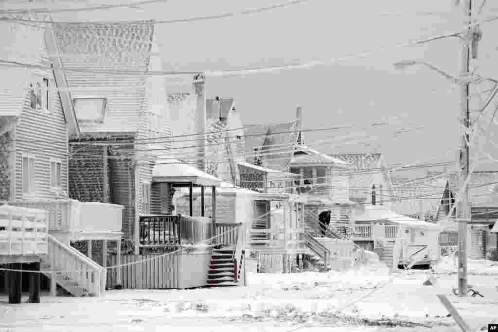 Dexter Newcomb begins cleanup at his house in Scituate, Mass., Jan. 28, 2015, the day after a winter storm left his neighborhood coated in frozen sea spray and sand.&nbsp;
