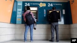 People use ATMs outside a closed branch of the Bank of Cyprus in capital Nicosia, Cyprus, Mar. 27, 2013.