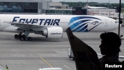 Un passager lit un journal dans un hall de départ du terminal Heathrow de Londres pendant qu’avion d’EgyptAir fait le taxi sur le tarmac de l'aéroport 20 mai 2016. REUTERS / Yannis Behrakis 
