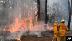 Petugas pemadam kebakaran tengah berupaya memadamkan api dekat sebuah rumah di wilayah Bilpin, 75 kilometer sebelah barat Sydney, Australia (22/10).