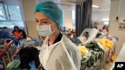 Seorang anggota staf medis berjalan di ruang isolasi COVID-19 yang ramai di Rumah Sakit Darurat Universitas di Bucharest, Rumania, 22 Oktober 2021. (Foto: AP)