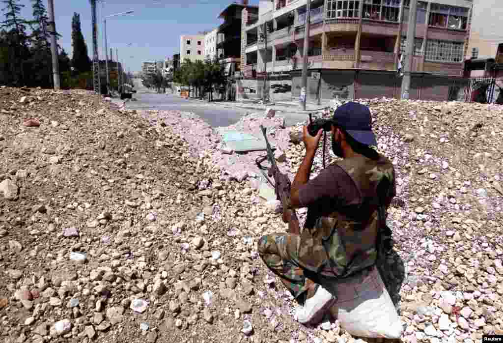 Anggota Tentara Pembebasan Suriah mengawasi lingkungan sekitarnya dengan binokular di Aleppo (13/8).