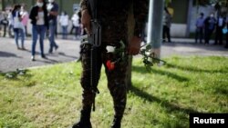 Un soldado sostiene flores fuera de las instalaciones de la Fuerza Aérea de El Salvador mientras los militares rechazaban una solicitud de un juez para acceder a los archivos sobre la masacre de El Mozote en 1981. 12 de octubre de 2020.