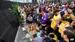Fans of Kobe Bryant mourn at a memorial to him in front of Staples Center, home of the Los Angeles Lakers, after word of the Lakers star's death in a helicopter crash, in downtown Los Angeles, Jan. 26, 2020.