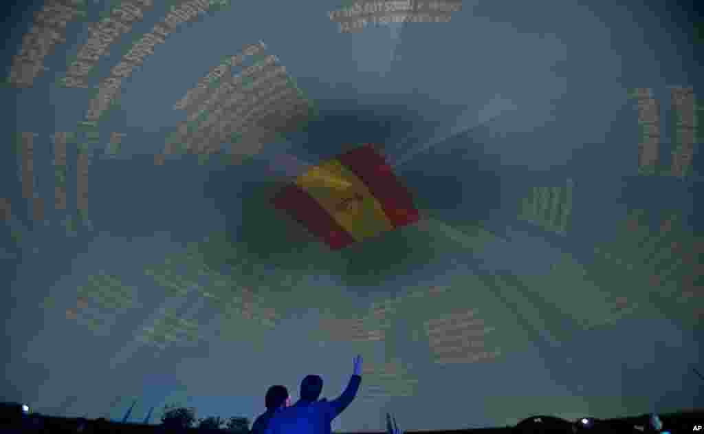 Seorang pria mengangkat tangan di bawah sebuah bendera Spanyol di ibukota Madrid, Warga Spanyol akan merayakan HUT konstitusi Spanyol tanggal 6 Desember.