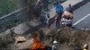Los residentes se paran al otro lado de una barricada levantada por personas que protestan contra el aumento de los precios de la gasolina y las políticas del presidente de Ecuador, Guillermo Lasso, en Quito, el 27 de octubre de 2021.
