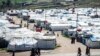 FILE - Women and children walk at Roj camp, where relatives of people suspected of belonging to the Islamic State group are held, in the countryside near al-Malikiyah in Syria's northeastern Hasakah province, on March 28, 2021.
