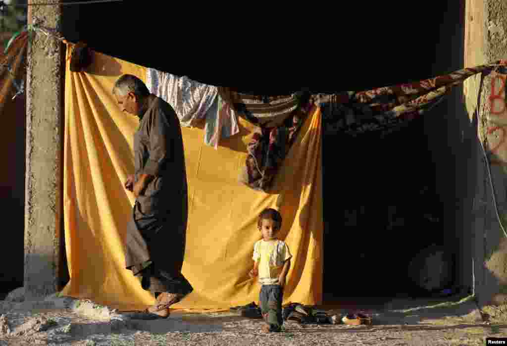 A Kurdish refugee and his child stand at the entrance of their temporary shelter in a refugee camp in the southeastern town of Suruc, Sanliurfa province, Oct. 5, 2014.